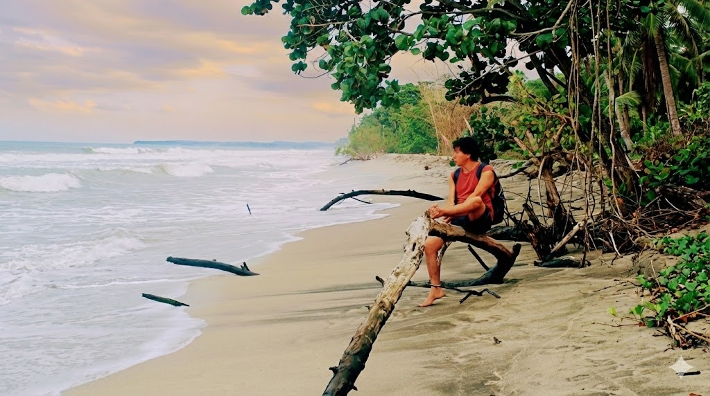Juan sentado en una playa tropical mirando hacia el mar